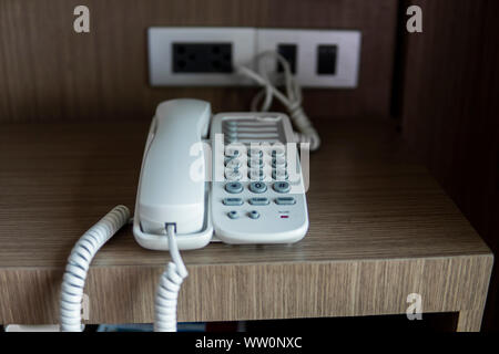 Vintage bianco telefono con battoms grigio su un tavolo marrone in hotel. Foto Stock