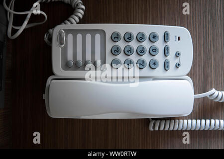 Vintage bianco telefono con battoms grigio su un tavolo marrone in hotel. Foto Stock