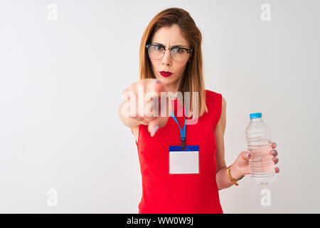 Redhead imprenditrice indossando id card acqua potabile isolato su sfondo bianco puntando con il dito per la telecamera e a voi, mano segno, positivo Foto Stock