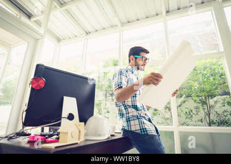 Giovani caucasici tenendo la sua bozza progetto presso la scrivania in ufficio a casa. Foto Stock