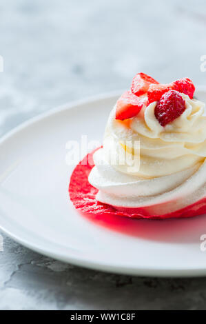 Uno splendido singoli Pavlova dessert su una piastra bianca. Close up. Foto Stock