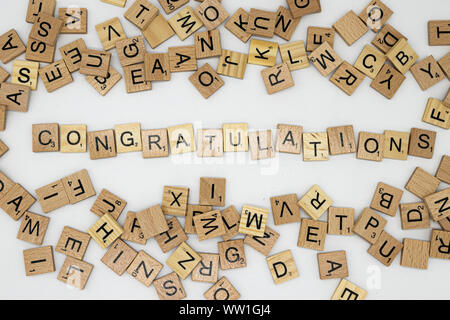 Messaggio di congratulazioni farro in lettere di scrabble circondato da varie piastrelle Foto Stock