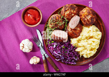 Crepinette, piatti fritti salsicce o le polpette di carne macinata e avvolto in un lobo grasso, servita su una piastra con purè di patate e cavolo rosso insalata, francese Foto Stock