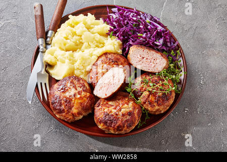 Crepinette, piatti fritti salsicce o le polpette di carne macinata e avvolti nel lobo grasso, servita su una piastra con purè di patate e cavolo rosso insalata, cu francese Foto Stock