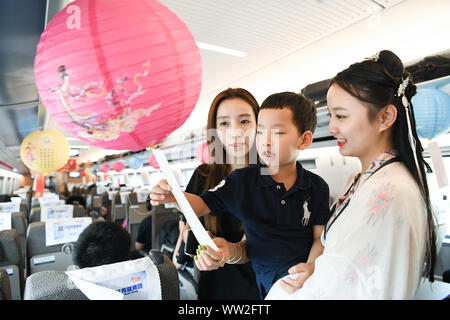 (190912) -- NANJING, Sett. 12, 2019 (Xinhua) -- una hostess del treno (1R) in cinese tradizionale costume e passeggeri indovinare lanterna enigmi per salutare il prossimo Mid-Autumn Festival a bordo di un treno bullet da Shanghai a Nanjing di oriente cinese della provincia di Jiangsu, Sett. 12, 2019. Mid-Autumn Festival cade il 7 settembre 13 Quest'anno. (Xinhua/Li Bo) Foto Stock