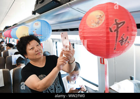 (190912) -- NANJING, Sett. 12, 2019 (Xinhua) -- un passeggero prende le immagini di una lanterna per salutare il prossimo Mid-Autumn Festival a bordo di un treno bullet da Nanjing di oriente cinese della provincia di Jiangsu a Shanghai, Sett. 12, 2019. Mid-Autumn Festival cade il 7 settembre 13 Quest'anno. (Xinhua/Li Bo) Foto Stock