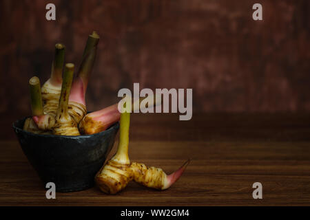 Ancora in vita con galangal in una coppa in ceramica su tavola in legno rustico, scegli un punto focale. Foto Stock