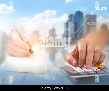 La mano viene premuto calcolatrice e scrivere carta, ci sono sovrapposizioni di edifici e città - un concetto di business, questa immagine si concentra sulla sfocatura da u Foto Stock