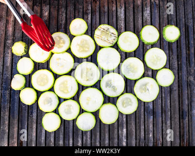 Per la cottura delle fette di zucchine su griglia di barbecue all'aperto Foto Stock