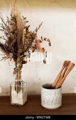 Bamboo naturale permanente dello spazzolino da denti in bagno sul ripiano di legno secco con fiori decorativi. Bagno essentials. Alla moda concetto eco. Foto Stock