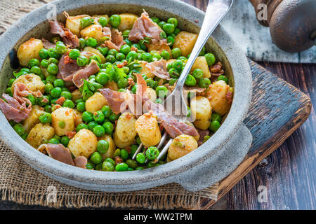 Gnocchi di patate con piselli verdi, pesto, prosciutto e il chorizo in una ciotola Foto Stock