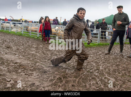 Kendal, Cumbria, Regno Unito. Xii Sep 2019. Le condizioni meteo didnt smorzare gli spiriti di tutti l'Westmorland County show, Kendal Cumbria, come questo fanciullo ha dimostrato, godendo di una diapositiva di fango. Non è certo che i suoi genitori ci è piaciuto tanto quanto ha fatto! Credito: Wayne HUTCHINSON/Alamy Live News Foto Stock