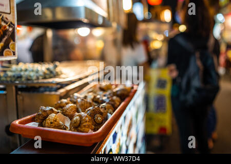 Taipei, Taiwan: Big Lumache con gusci di cibo di strada venditore al Mercato Notturno di Raohe con sfondo sfocato Foto Stock