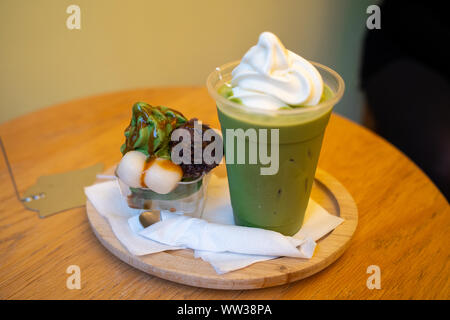 Tazza di iced Matcha Grean tè cappuccino con panna e una ciotola di Matcha gelato con fagioli azuki incolla e Mochi con nero sirup di zucchero Foto Stock