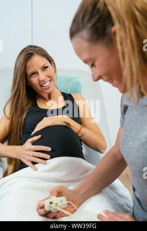 Paziente donna incinta osserva la sua balia mentre ella controlla le contrazioni. Concetto di buona salute. L'immagine verticale Foto Stock