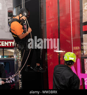 L'artista di strada Alec Monoploy abseils giù la flanelle store su Oxford Street, Londra in occasione della celebrazione del suo lancio di apertura. Foto Stock