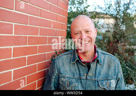 Ritratto di uomo sorridente di fronte a un muro di mattoni giornata soleggiata in California Foto Stock