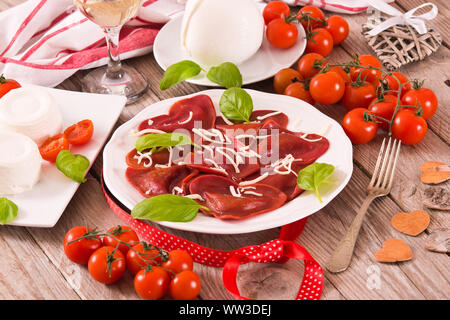 Cuore rosso ravioli con pomodoro, mozzarella e basilico. Foto Stock