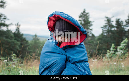 Ritratto di una donna avvolta in un sacco a pelo campeggio selvaggio all'aperto Foto Stock