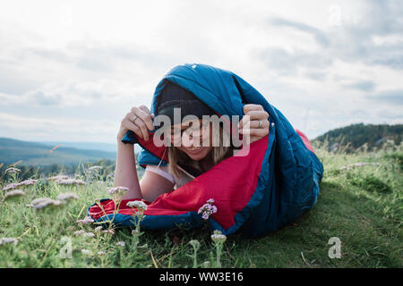 Ritratto di donna campeggio selvaggio avvolto in un sacco a pelo Foto Stock