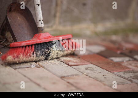 Scopa e paletta su un pavimento piastrellato in pietra nel cortile Foto Stock