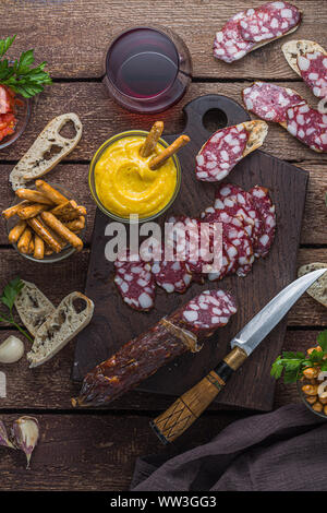 Vino rosso snack set. Salame, anchoves, pomodori e crosta di pane. laici piatta Foto Stock