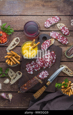 Charcuterie scheda con salame e alioli dip, vino rosso. Foto Stock