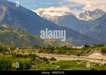 Vista in elevazione della valle con il Priorato di Saint-Pierre, le rovine del castello di Châtel-Argent di Villeneuve e il Mont Blanc range, Aosta, Italia Foto Stock