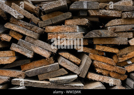 Piegate il vecchio legno marrone e grigio di tavole in una segheria. Impilate le schede ontano texture Foto Stock