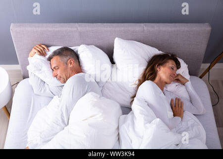 Angolo di Alta Vista della Coppia Matura che dorme sul letto di casa Foto Stock