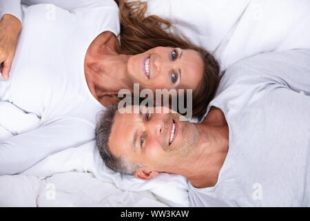 Angolo di Alta Vista di Felice Coppia Matura giacente sul letto Foto Stock