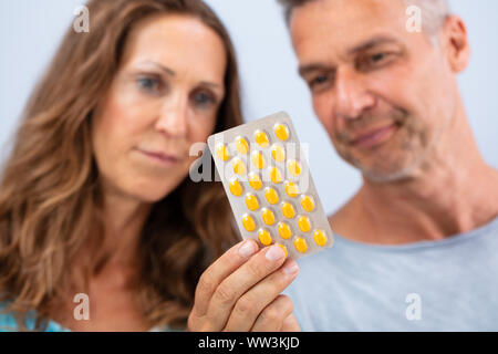 Sorridente uomo maturo che mostra la sua moglie compressa giallo Blister Foto Stock