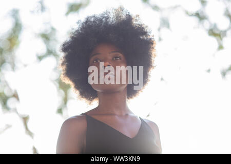 Giovane africano donna americana shot dal di sotto, fiducioso look, determinata Foto Stock