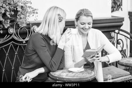 Discutendo popolare libro best-seller. Letteratura femminile. Prenota ogni ragazza dovrebbe leggere. Ragazze amici seduti cafe terrazza a bere caffè. La lettura del libro ispiratore. Miglioramento di auto e l'istruzione. Foto Stock