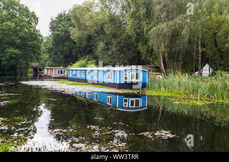 In legno di colore blu casa galleggiante ormeggiato sulle rive del Basingstoke Canal vicino eremo, Woking, Surrey, Inghilterra sudorientale, REGNO UNITO Foto Stock