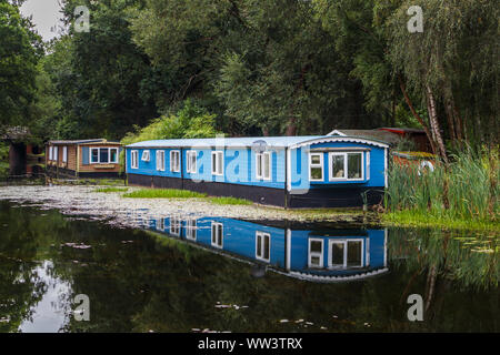 In legno di colore blu casa galleggiante ormeggiato sulle rive del Basingstoke Canal vicino eremo, Woking, Surrey, Inghilterra sudorientale, REGNO UNITO Foto Stock