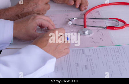 Medico mani con cardiogram grafico con penna. Cardiologo spiegando il suo paziente EKG risultati. Foto Stock