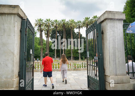 Atene GRECIA - Luglio 15 2019; giovane a piedi attraverso il cancello aperto della Grecia il Giardino Nazionale Foto Stock