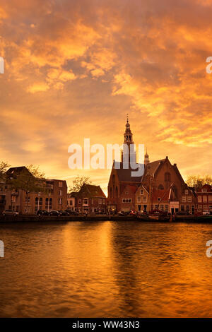 Il centro storico di Maassluis, Paesi Bassi lungo il porto. Sunrise si illumina dietro di antichi edifici vecchi. Tramonto dietro la vecchia chiesa. Paesaggio panoramico Foto Stock