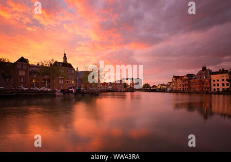 Il centro storico di Maassluis, Paesi Bassi lungo il porto. Sunrise si illumina dietro di antichi edifici vecchi. Tramonto dietro la vecchia chiesa. Paesaggio panoramico Foto Stock