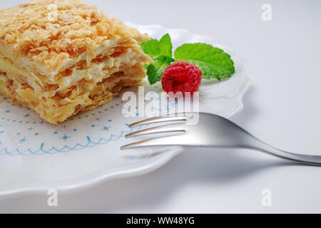 Torta Napoleone con vaniglia e crema di latte su una piastra isolata su sfondo bianco Foto Stock
