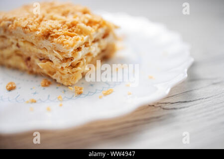 Torta Napoleone con vaniglia e crema di latte su una piastra isolata su sfondo bianco Foto Stock