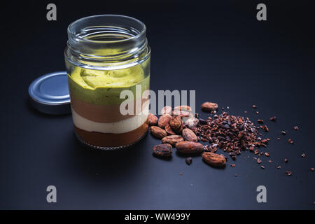 Il latte cremoso dessert in vaso con noci, cioccolato e chicchi di cacao isolato Foto Stock