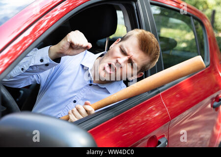 Driver arrabbiato con la mazza da baseball urlando al di fuori della finestra di auto Foto Stock