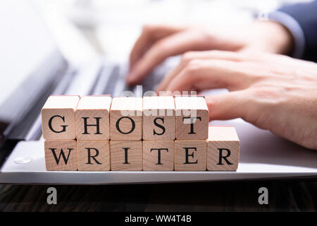 Un Ghostwriter blocco di legno sulla tastiera del computer mentre qualcuno digita Foto Stock