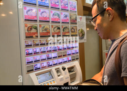 Un uomo giapponese di acquisto di un biglietto di pasto fuori del ristorante prima di entrare, è una soluzione per il lavoratore la carenza e l'efficienza in Tokyo, Giappone. Foto Stock