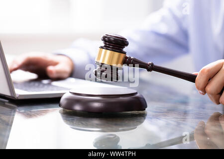 Giudice Maschio in un aula di tribunale digitando su laptop in prossimità di un mazzuolo Foto Stock