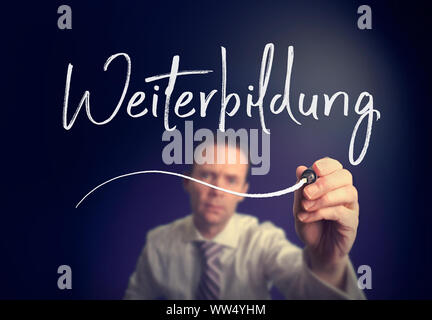 Un imprenditore iscritto un ulteriore istruzione "Weiterbildung' concetto in tedesco con una penna bianca su uno schermo chiaro. Foto Stock