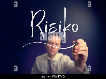 Un imprenditore iscritto un rischio "Risiko' concetto in tedesco con una penna bianca su uno schermo chiaro. Foto Stock