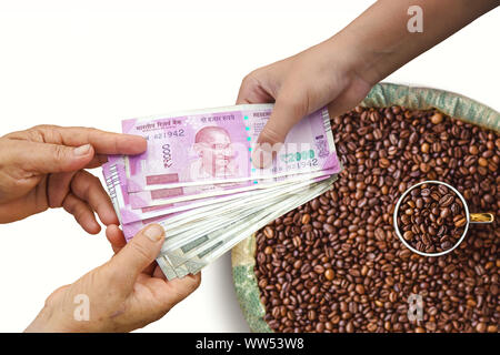 Mano dando Indian 500 e 2000 rupie banconote oltre il sacchetto,tela piena di caffè in grani, il concetto di utili o di trascorrere in agricoltura. Foto Stock